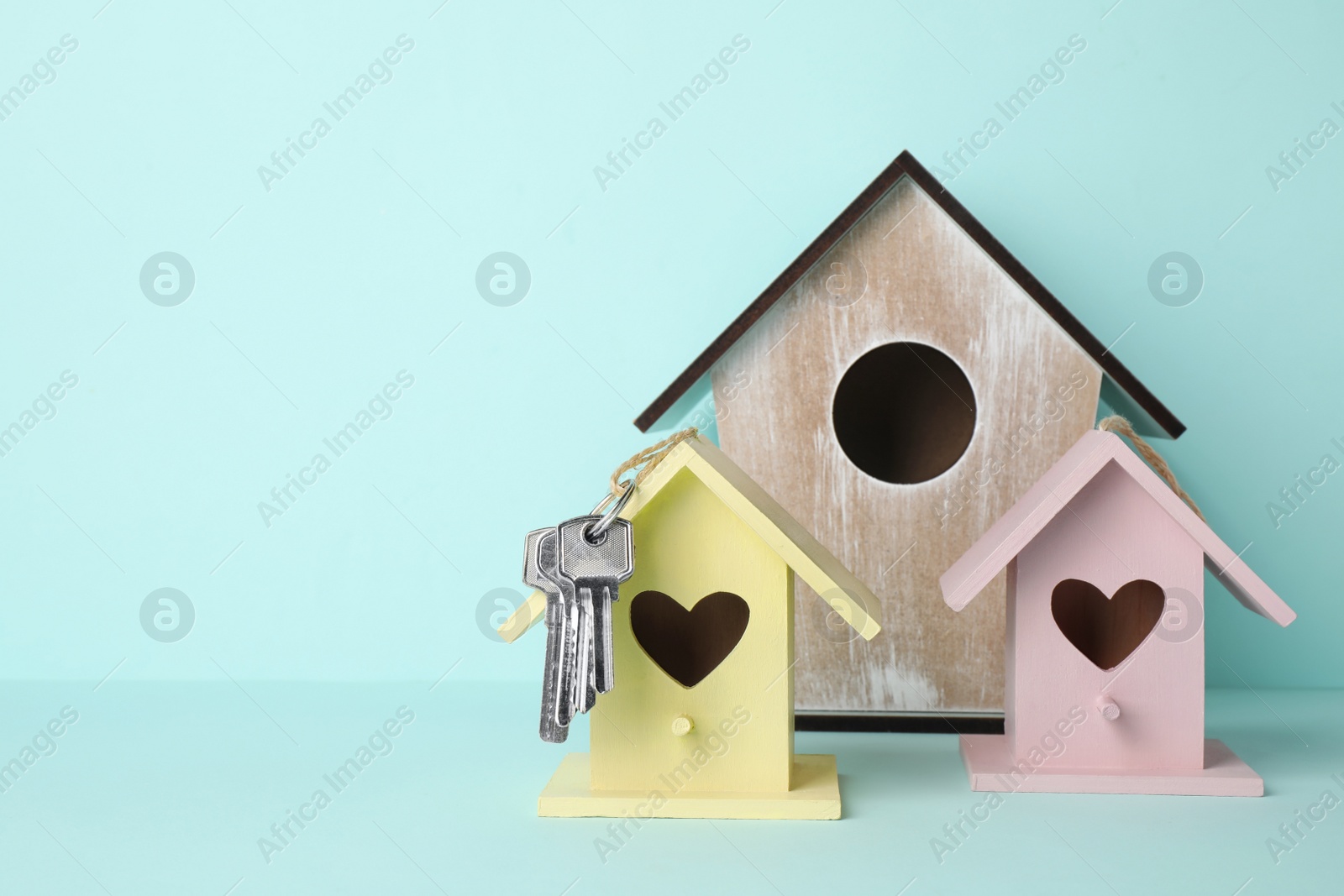 Photo of Decorative bird houses and keys on light blue background. Space for text