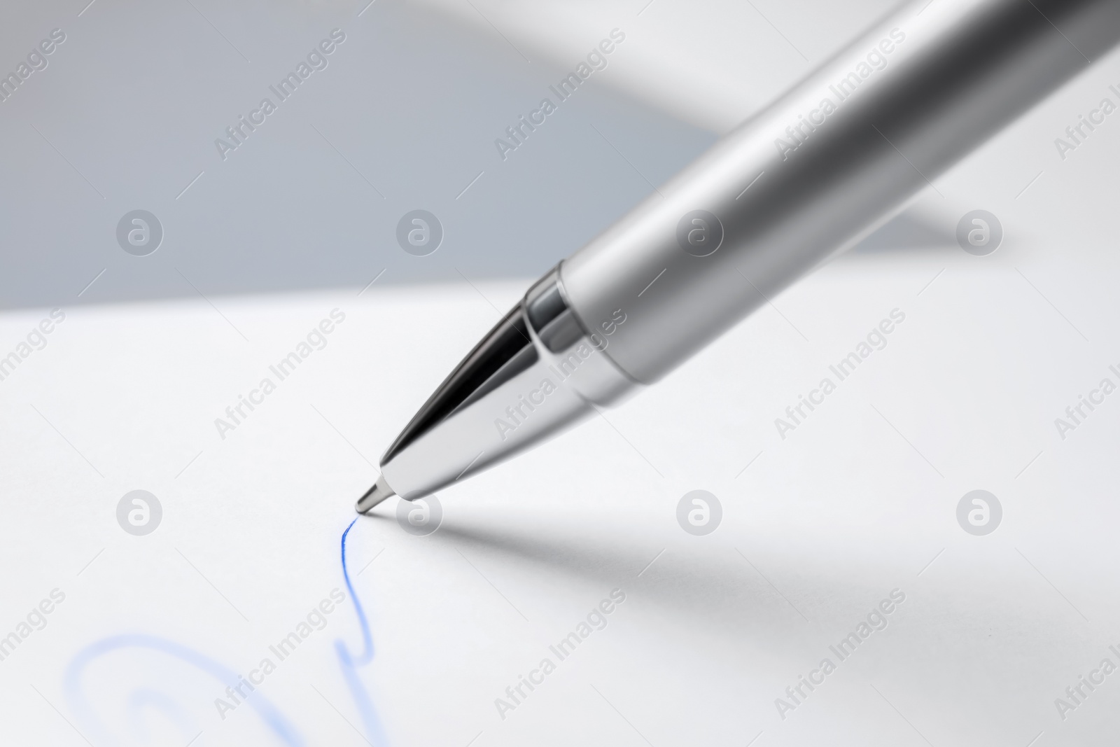 Photo of Signing on sheet of white paper with pen, closeup