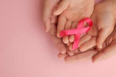 Photo of Woman and child holding pink ribbon on color background, top view with space for text. Breast cancer awareness