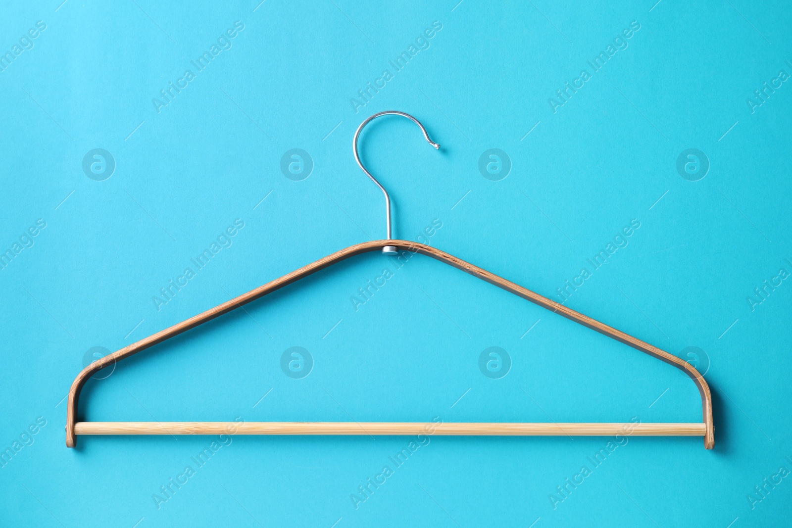 Photo of One wooden hanger on light blue background, top view