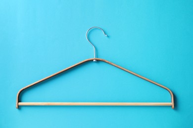 One wooden hanger on light blue background, top view