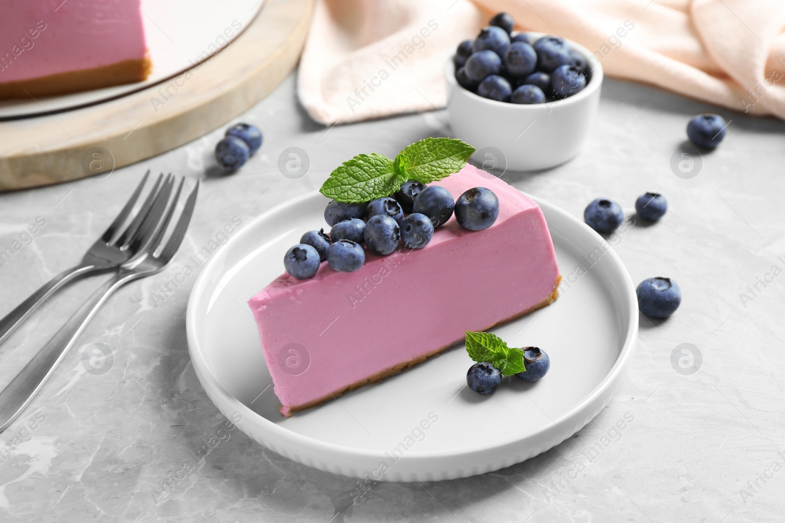 Photo of Plate with piece of tasty blueberry cake on light table