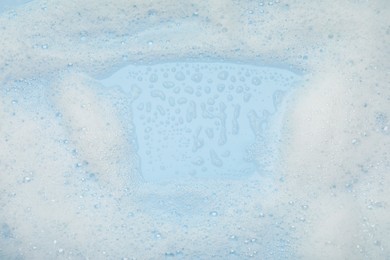 White washing foam on light blue background, top view