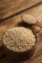 Bowl with white quinoa on wooden table. Space for text