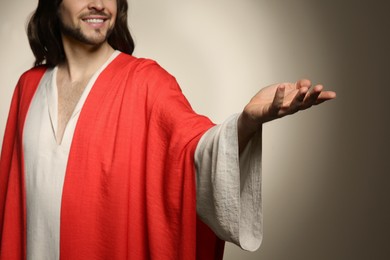 Photo of Jesus Christ reaching out his hand on beige background, closeup
