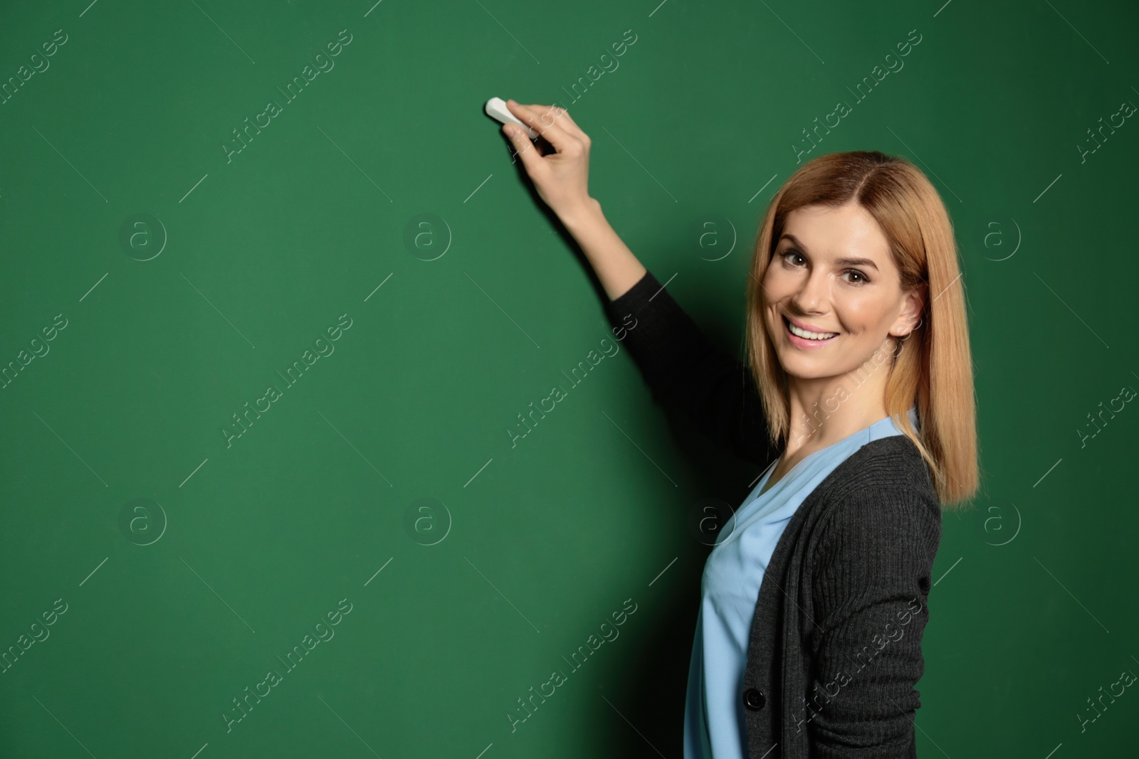 Photo of Beautiful teacher writing on chalkboard, space for text