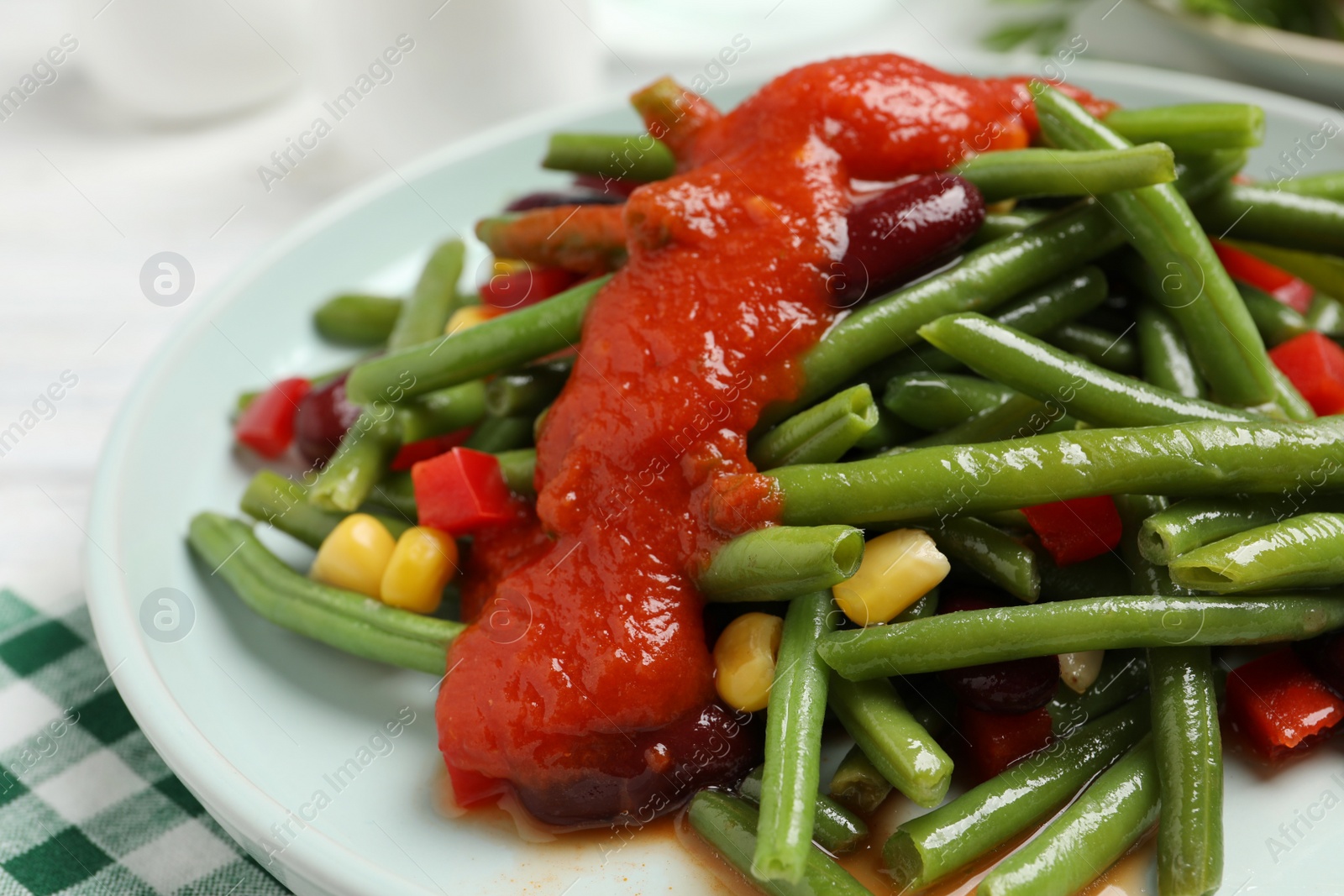 Photo of Delicious salad with green beans and tomato sauce on table, closeup