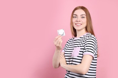 Photo of Woman holding condom on pink background, space for text. Safe sex
