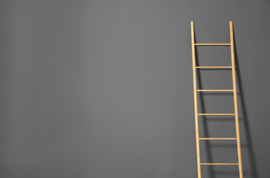 Photo of Modern wooden ladder on grey background. Space for text