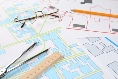 Photo of Office stationery and eyeglasses on cadastral maps of territory with buildings