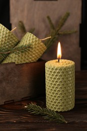 Photo of Stylish elegant beeswax candles with spruce branches on wooden table