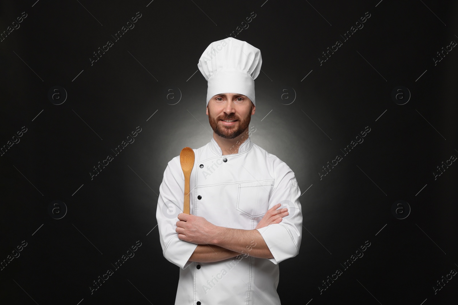 Photo of Mature chef with spoon on black background