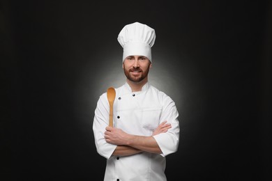 Photo of Mature chef with spoon on black background