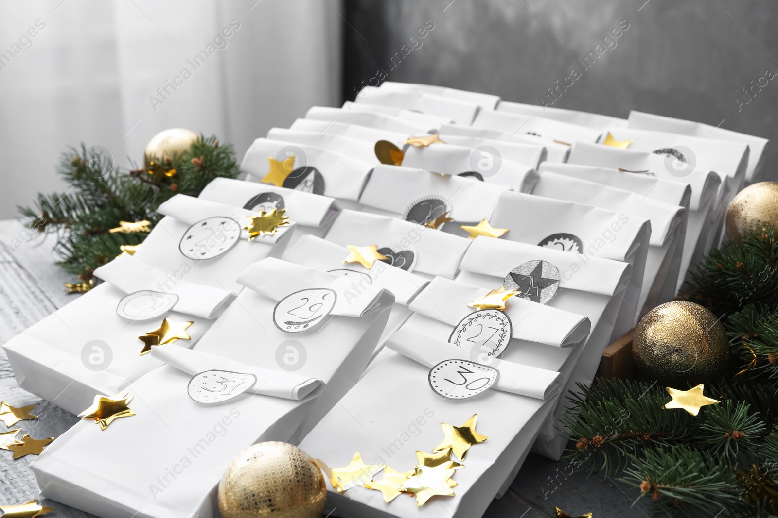 Photo of Christmas advent calendar with gifts and festive decor on grey wooden table