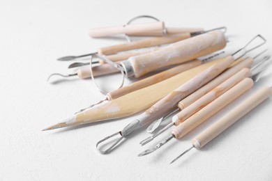 Set of different clay crafting tools on white table