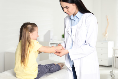 Photo of Professional orthopedist examining little patient's arm in clinic