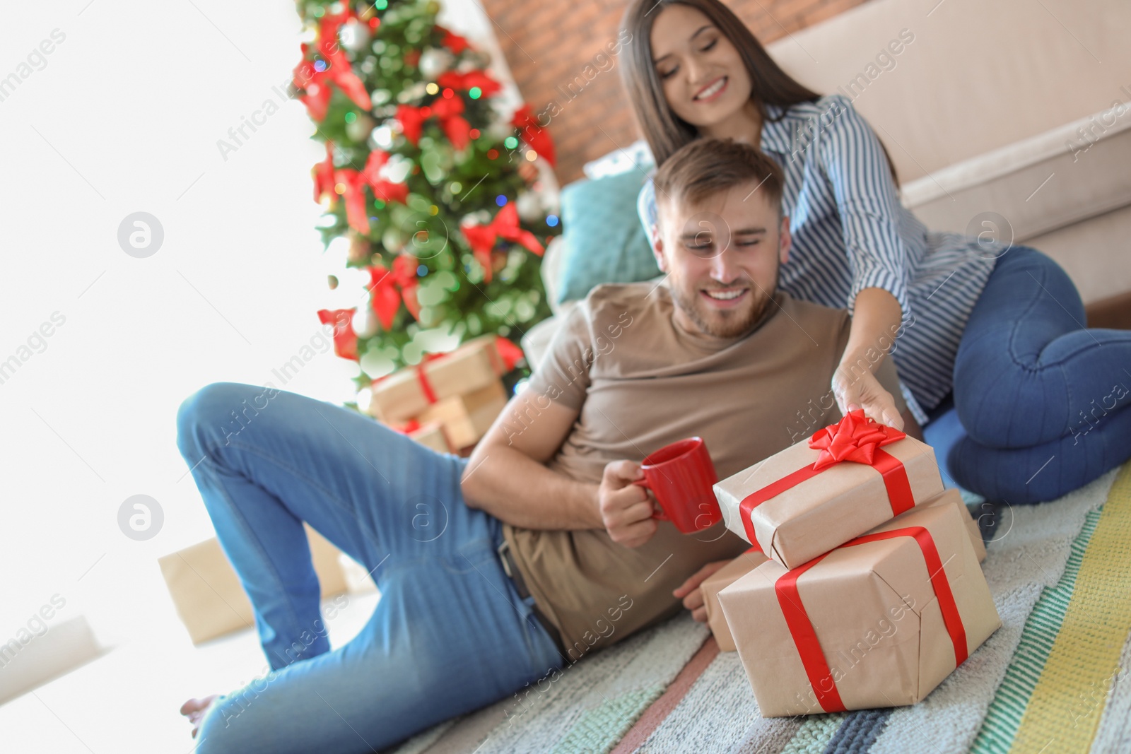 Photo of Happy young couple with Christmas gifts at home