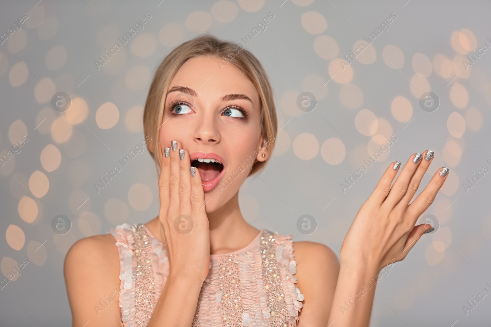 Photo of Portrait of emotional young woman with shiny manicure on blurred background. Nail polish trends