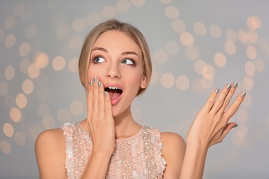 Portrait of emotional young woman with shiny manicure on blurred background. Nail polish trends