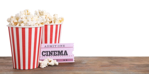 Cups with delicious popcorn and tickets on wooden table against white background