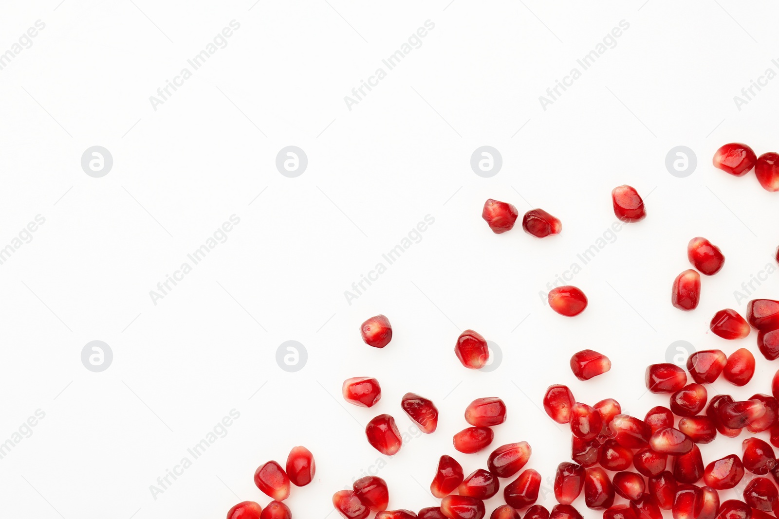 Photo of Many ripe juicy pomegranate grains on white background, flat lay. Space for text