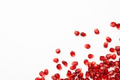 Many ripe juicy pomegranate grains on white background, flat lay. Space for text