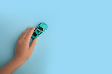 Photo of Child playing with toy car on light blue background, top view. Space for text