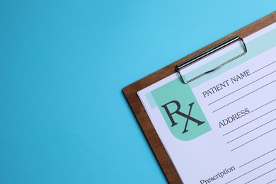 Photo of Clipboard with medical prescription form on light blue background, top view. Space for text