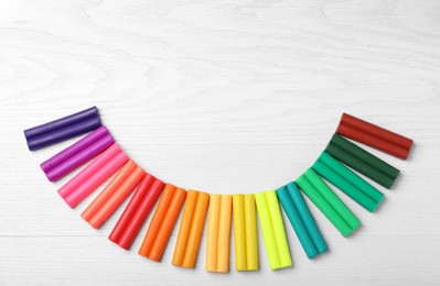 Photo of Many different colorful plasticine on white wooden table, flat lay. Space for text