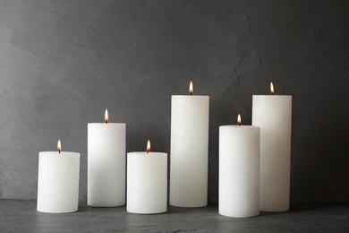 Photo of Many alight scented wax candles on table