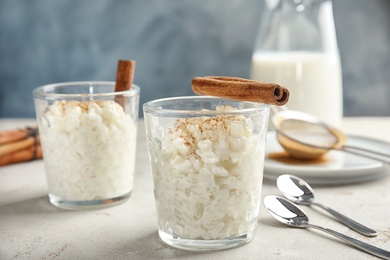 Photo of Creamy rice pudding with cinnamon in glasses on table