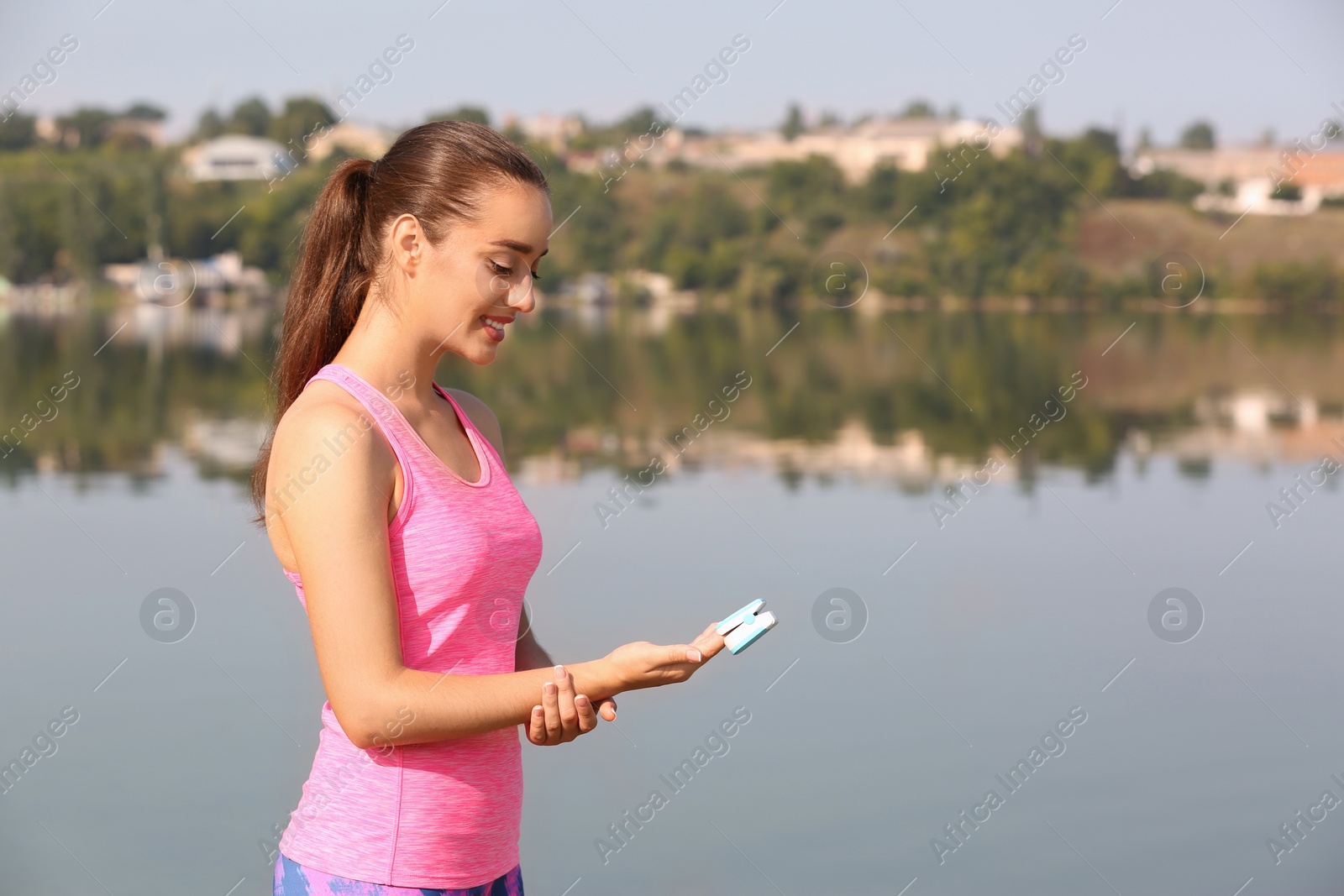 Photo of Young woman checking pulse outdoors on sunny day