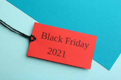 Red tag with words BLACK FRIDAY 2021 on color background, top view
