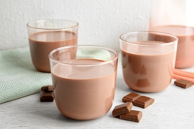 Photo of Glasses with tasty chocolate milk on wooden table. Dairy drink