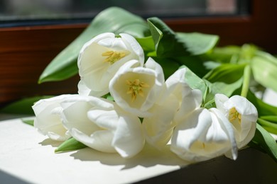 Photo of Bouquet of beautiful white tulip flowers on windowsill indoors, closeup