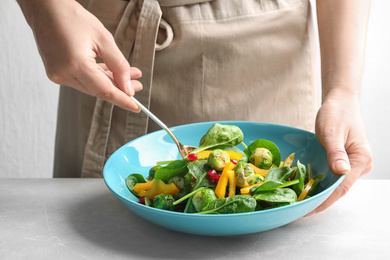 Photo of Woman preparing tasty salad with Brussels sprouts at grey table, closeup