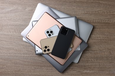 Many different modern gadgets on wooden table, top view