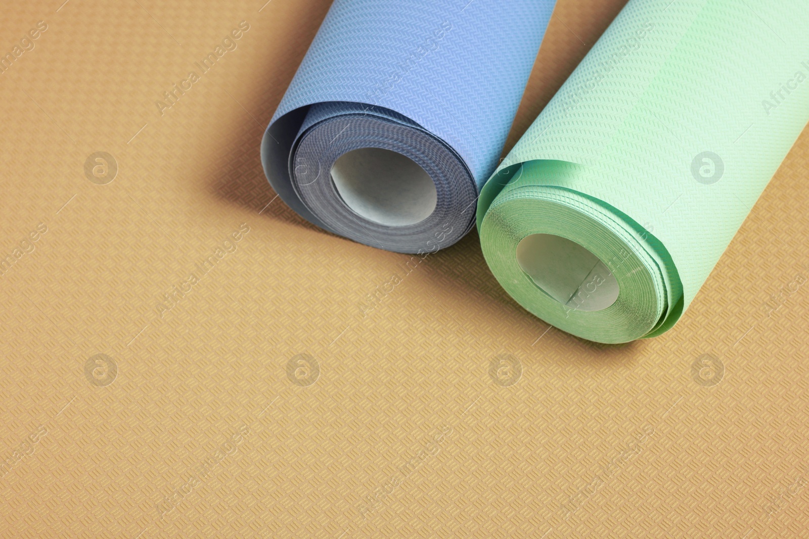 Image of Colorful wallpaper rolls on orange background, closeup