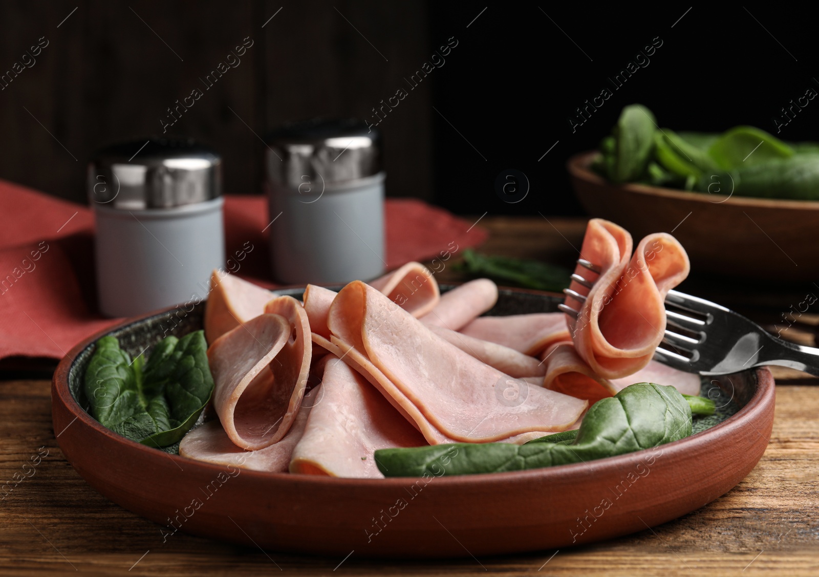 Photo of Tasty ham with fresh spinach on table