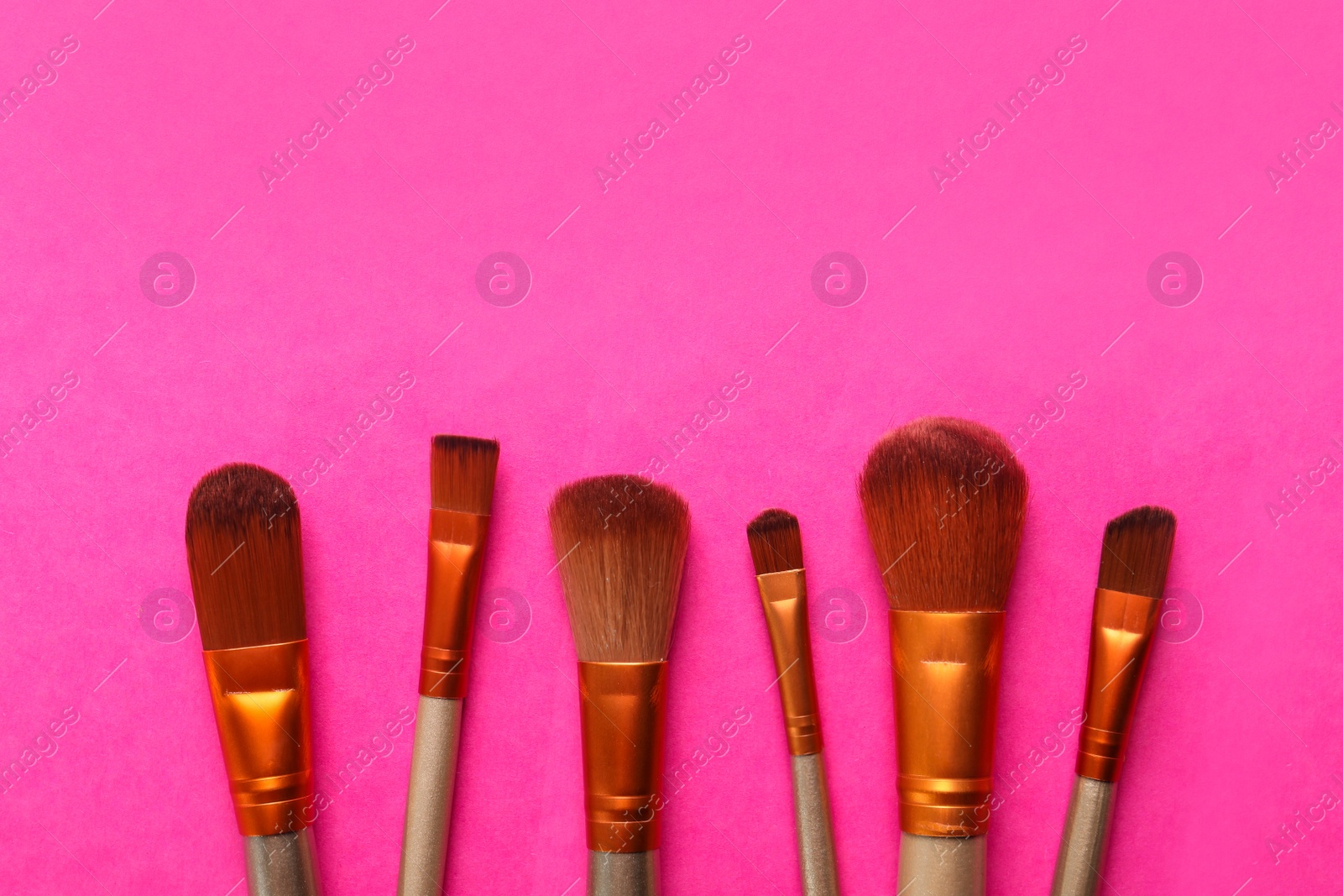 Photo of Different makeup brushes on pink background, flat lay. Space for text