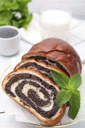 Photo of Slices of poppy seed roll and mint on table, closeup. Tasty cake