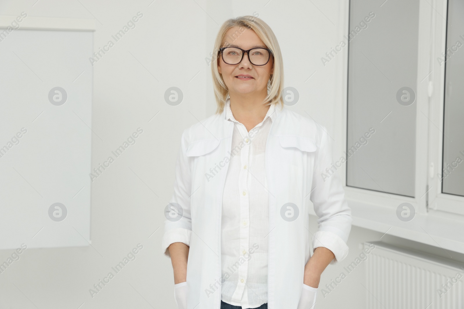 Photo of Professional doctor wearing medical coat near flipchart board in clinic