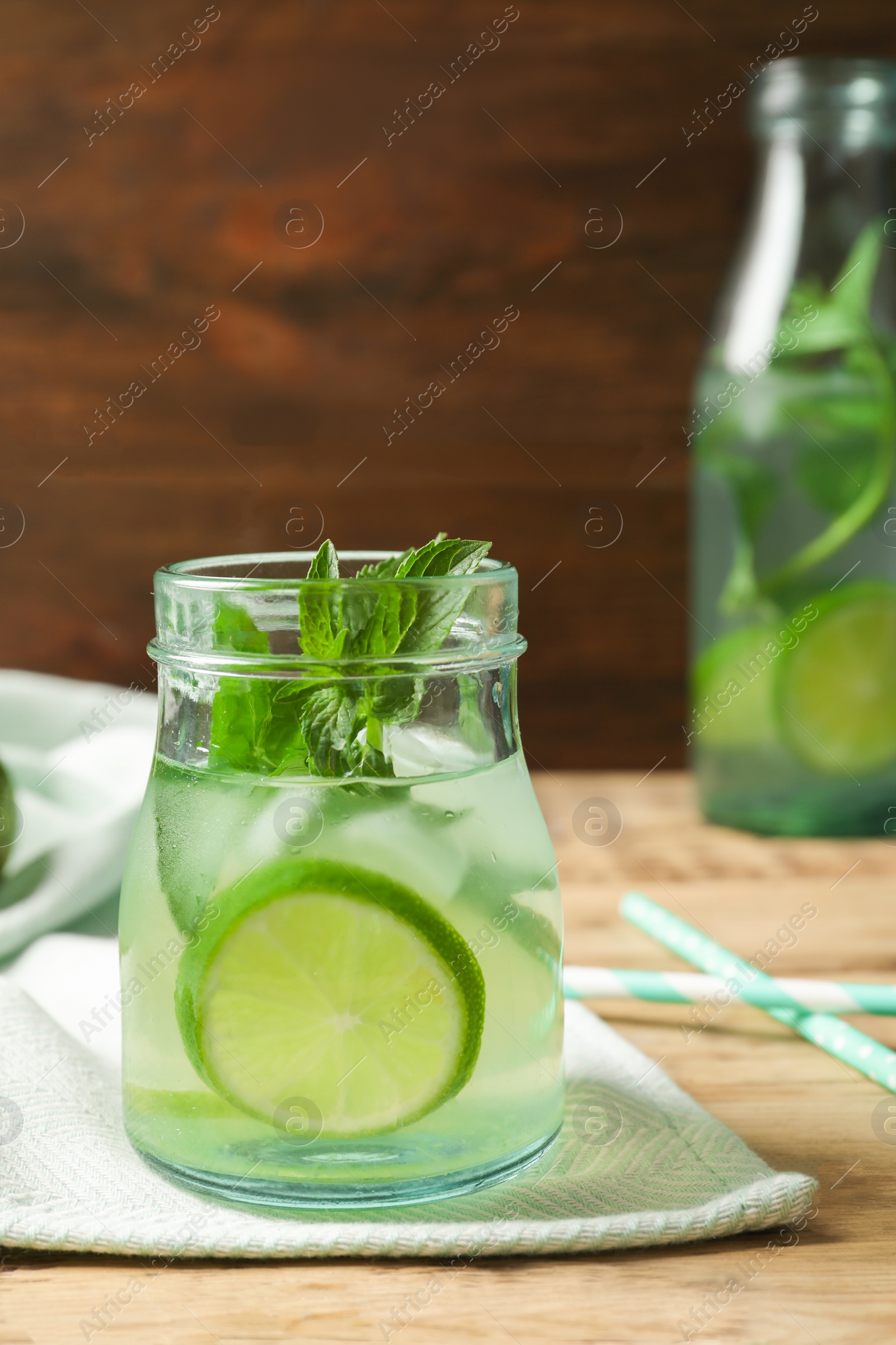 Photo of Natural lemonade with lime in jar on wooden table