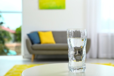 Glass of water on table in room, space for text. Refreshing drink