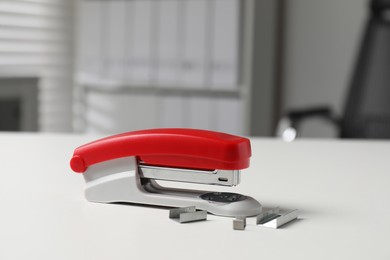 Stapler and metal staples on white table indoors