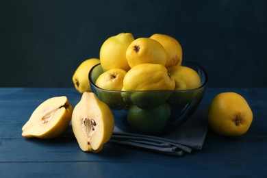Photo of Tasty ripe quinces in bowl on blue wooden table