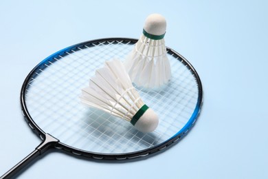 Photo of Feather badminton shuttlecocks and racket on light blue background, closeup