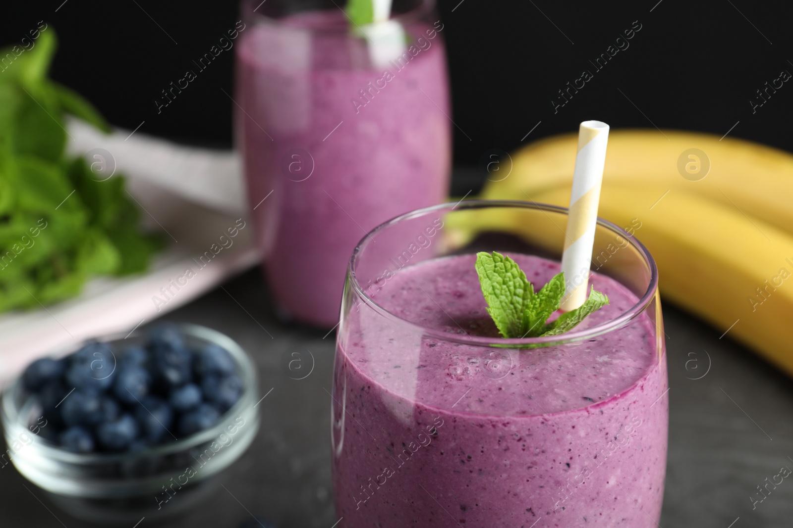 Photo of Delicious blueberry smoothie served on grey table, closeup