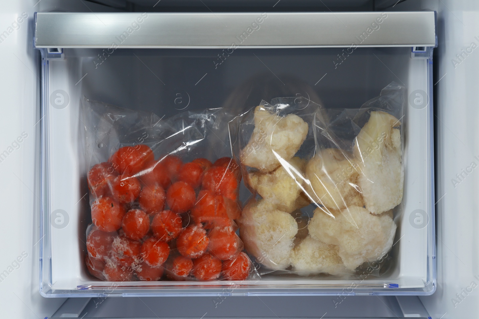 Photo of Bags with frozen vegetables in modern refrigerator