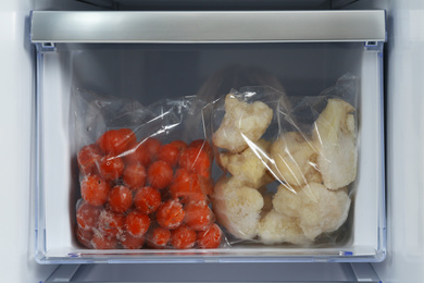 Photo of Bags with frozen vegetables in modern refrigerator